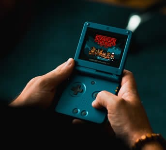 Handheld gaming console displaying Stranger Things game, nostalgic gaming device.